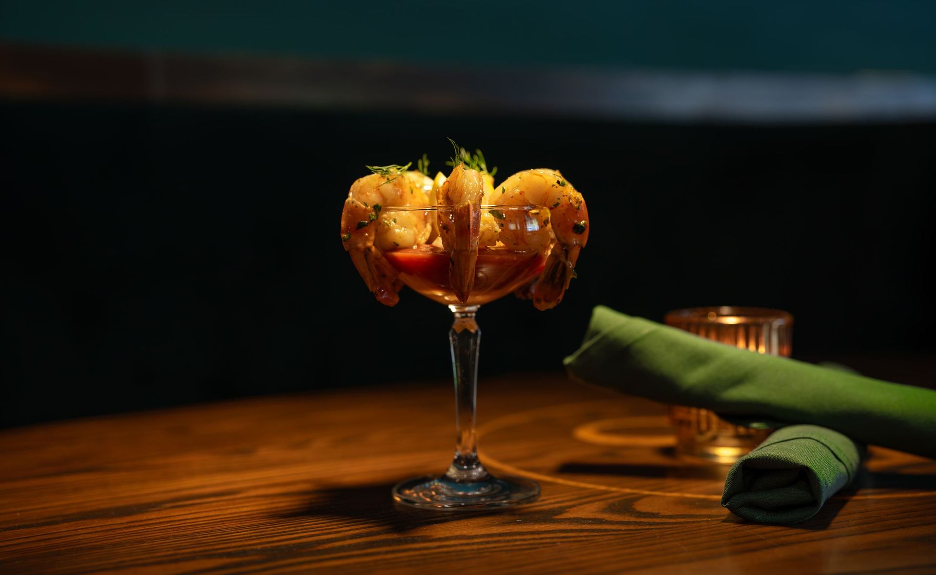 Jumbo shrimp cocktail in a coupe glass on a wood table